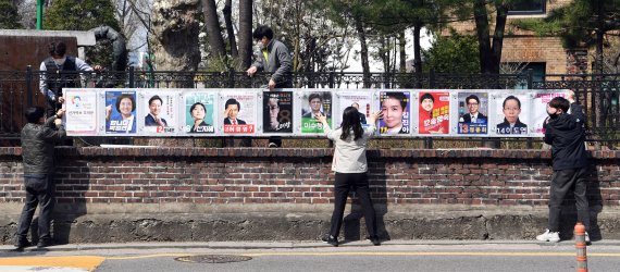 서울특별시선거관리위원회 직원들이 25일 서울 종로구 이화동 예술가의집 울타리에 '4·7 서울시장 보궐선거'에 출마하는 후보자들의 선거벽보를 붙이고 있다.<div id='ad_body3' class='mbad_bottom' ></div> 사진=박범준 기자