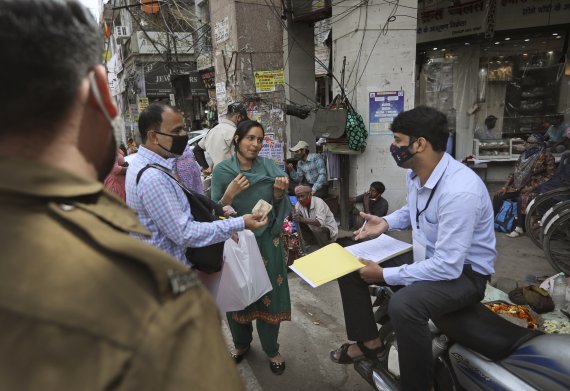 지난 3월25일(현지시간) 인도 뉴델리의 한 시장에서 마스크를 착용하지 않은 부부가 벌금을 지불하고 있다.AP뉴시스
