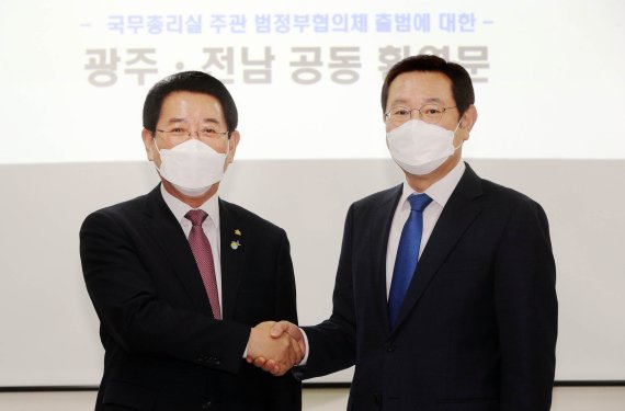 김영록 전라남도지사와 이용섭 광주시장이 31일 나주시 빛가람동 광주전남연구원에서 만나 총리실 주관 범정부 협의체 출범에 대한 공동 환영문을 발표에 앞서 인사를 나누고 있다.(전남도 제공) 2021.3.31/뉴스1 © News1