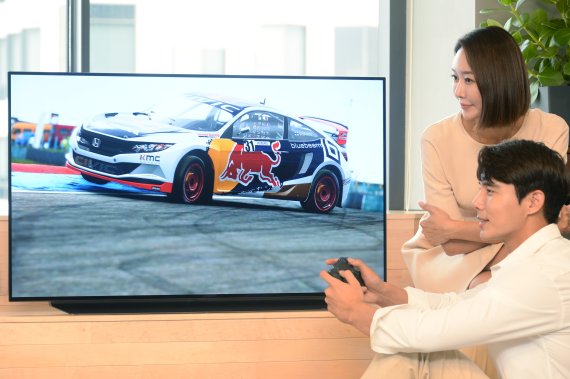 LG전자 모델이 48형 올레드 TV로 게임을 즐기며 제품을 소개하고 있다.