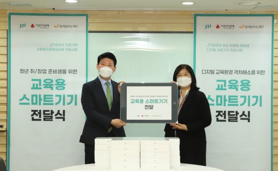 JTI코리아 정경일 전무(왼쪽)와 함께일하는재단 박지영 사무국장이 스마트기기 전달식에서 기념촬영을 하고 있다.