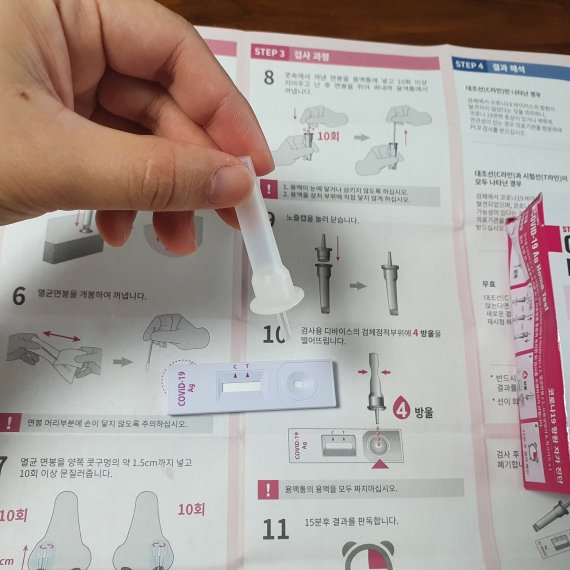 용액통 노즐캡을 닫고 검사용기기에 용액통을 짰다. 검가용기기 검체점적부위에 4방울을 떨어뜨리면 된다. 2분 정도 기다지라 검사용기기에 분홍색 한 줄 선이 생겼다. 사진=최용준 기자.