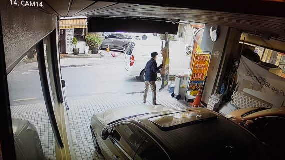정체 불상의 사람이 식당 앞에 승합차를 세운 뒤 오비맥주 '한맥' 입간판을 무단으로 수거해 트렁크에로 실고 있다. (오비맥주가 입수해 경찰에 증거로 제출한 CCTV 영상 일부. © 뉴스1