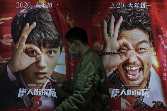 [베이징=AP/뉴시스]25일 중국 베이징의 폴리시네마에서 코로나19 확산 방지를 위해 마스크를 쓴 한 남성이 영화 '당인가탐안3' 포스터를 앞을 지나고 있다. 코로나19 방역 수칙을 철저히 지키고 영화관 내 관람객을 50~75%로 유지하면서 2월까지 중국 영화들의 실적이 할리우드 영화를 앞질러 박스오피스 기록을 경신한 것으로 나타났다. 2021.02.26.