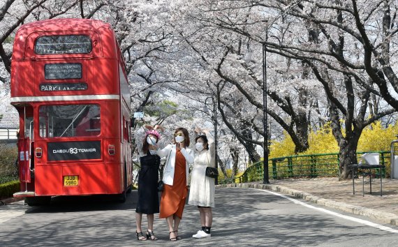 [대구=뉴시스] 이무열 기자 = 완연한 봄 날씨를 보인 25일 대구 달서구 놀이공원 이월드를 찾은 외국인 관광객들이 활짝 핀 벚꽃을 배경으로 기념사진을 찍고 있다. 2021.03.25. lmy@newsis.com