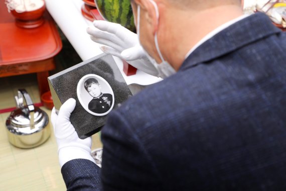 어린이날인 5일 광주 북구 운정동 국립 5·18민주묘지 故전재수군 묘역에서 형 전재룡씨가 동생 묘비 사진을 바꾼 후 눈물을 닦고 있다. 2021.5.5/뉴스1 © News1 허단비 기자