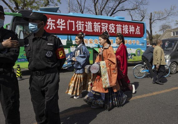 지난 4월 14일 중국 베이징의 자금성 주변에서 전통 의상을 입은 주민들이 무료로 코로나19 백신 접종을 제공하는 버스 앞을 지나고 있다. /사진=뉴시스