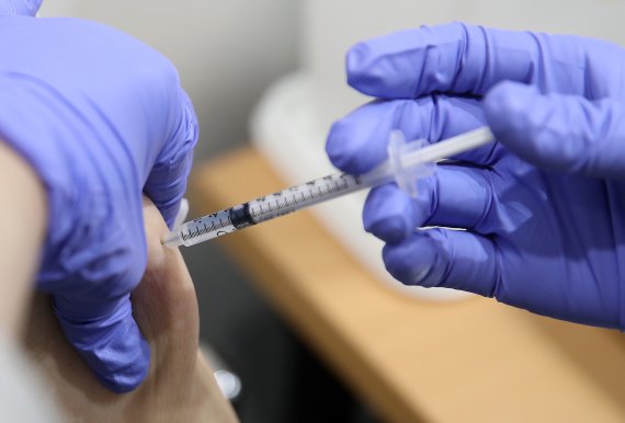 한 의료진이 코로나19 백신을 접종하기 위해 접종자의 팔에 주사바늘을 꼽고 있다. /사진=뉴시스