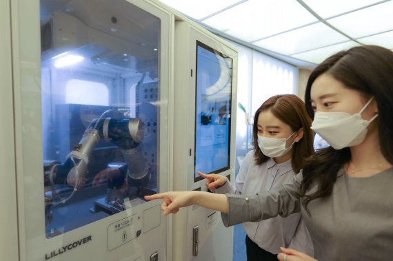 AK플라자 분당점에 오픈한 '릴리커버' 팝업 매장에서 고객들이 화장품을 만들고 있는 스마트팩토리를 지켜보고 있다.