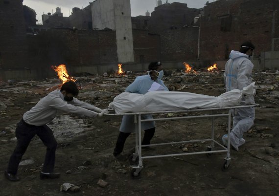 인도 뉴델리 임시 화장터에서 사람들이 코로나19 희생자를 화장하기 위해 시신을 옮기고 있다. 뉴시스
