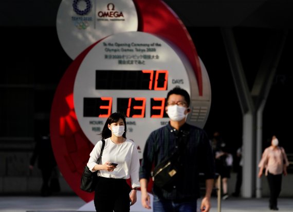 14일 일본 도쿄, 도쿄올림픽이 '70일' 남았다는 것을 알리는 시계탑 앞을 마스크를 쓴 행인들이 지나가고 있다. 로이터 뉴스1