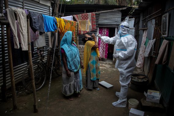 인도 아삼주 가우하티의 한 빈민가에서 17일(현지시간) 방역요원이 보호복을 입고 주민들에게서 코로나19 검사를 위함 검체를 채취하고 있다. AP뉴시스