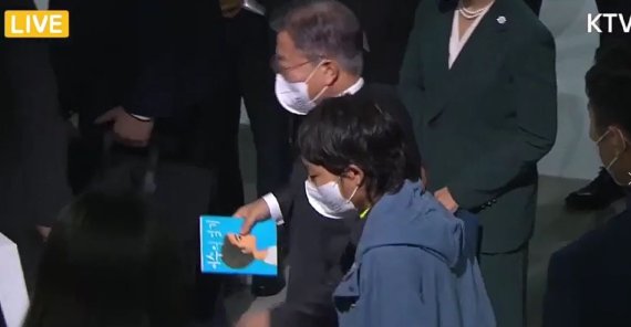 전이수 작가에게 선물받은 책을 손에 들고 있는 문재인 대통령 /사진=KTV
