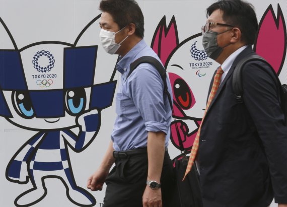 지난 16일 도쿄 중심가. 도쿄올림픽 홍보 포스터 앞으로 마스크를 쓴 사람들이 지나가고 있다. AP뉴시스