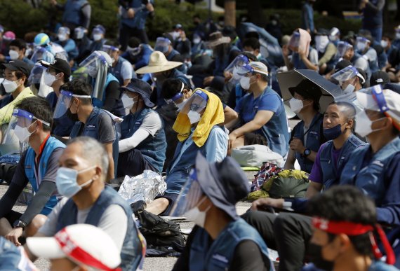전국택배노동조합 회원들이 지난 16일 서울 여의도공원에서 열린 문화제에서 우산을 쓰거나 수건 등으로 머리를 가려 뜨거운 햇빛을 피하고 있다. 뉴시스
