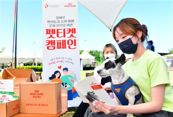 전북 임실군 오수의견관광지에서 진행되는 ‘반려동물과 함께하는 차박캠핑’ 행사에 참여한 반려가족이 ‘펫티켓 가이드북’을 읽고 있다. 로얄캐닌코리아 제공.