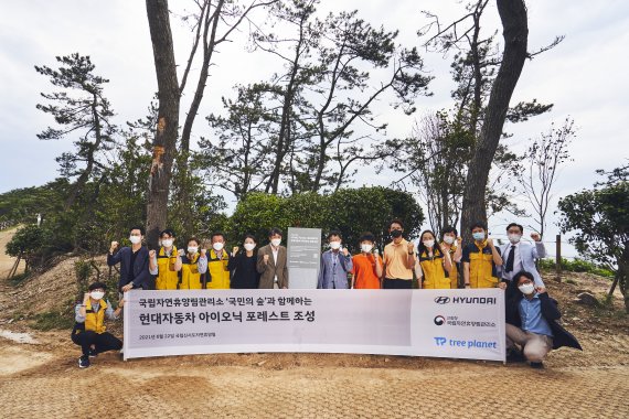 지난 22일 국립신시도자연휴양림에서 열린 ‘국민의 숲’ 협약을 체결식에서 현대차 CSV전략팀 최원준 팀장 (중앙 현판 왼쪽), 국립자연휴양림관리소 이영록 소장(중앙 현판 오른쪽) , 트리플래닛 임직원 등 주요 관계자들과 신시도 초등학교 학생 및 교사들이 기념 촬영을 하고 있다. 현대차 제공