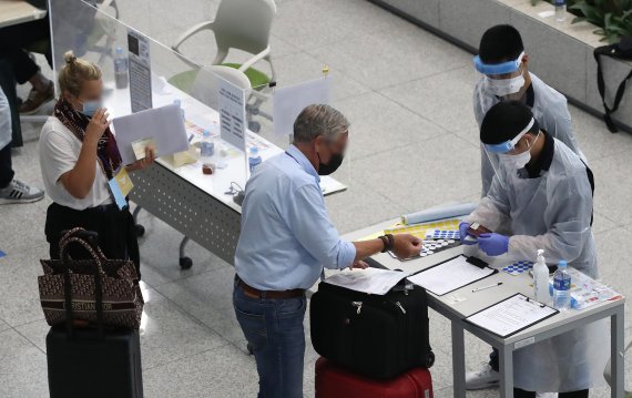 지난 21일 인천국제공항 제2여객터미널에서 방역 관계자들이 해외 입국자들에게 동선을 안내하고 있다. 뉴스1 제공