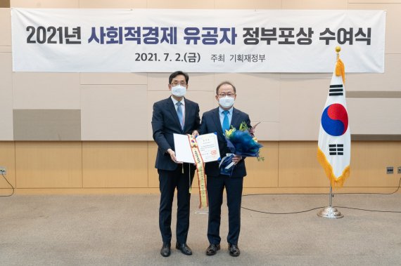 KT&G가 지난 2일 '2021 사회적경제 유공자' 정부포상 수여식에서 대통령 표창을 수상했다. 사진은 이상학 KT&G 지속경영본부장(오른쪽)이 수여식에 참석해 기념촬영을 하고 있는 모습. /사진=KT&G