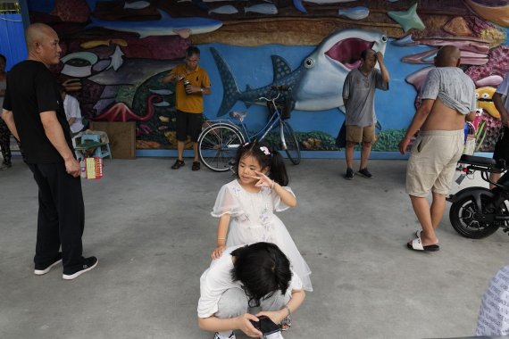 중국 베이징의 수족관을 그려 놓은 벽화 앞에서 13일 시민들이 아이들과 함께 휴식을 취하고 있다. AP뉴시스