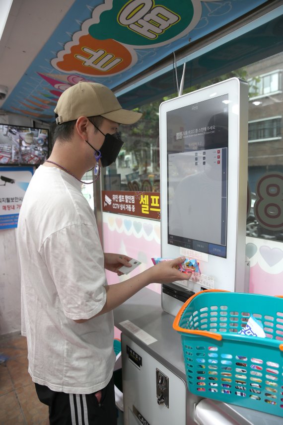 최저임금 인상 여파로 가맹점의 인건비 부담이 증가하면서 무인 판매 관련 시장이 더욱 커질 전망이다. 지난 14일 서울 시내의 한 무인 아이스크림 가게에서 고객이 아이스크림을 구매하고 있다.