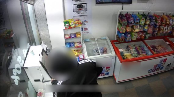 특수절도 혐의로 구속된 30대 A씨가 파주시의 한 24시간 아이스크림 무인점포에서 현금계산기를 도구를 이용해 열고 있다. (파주경찰서 제공) © 뉴스1