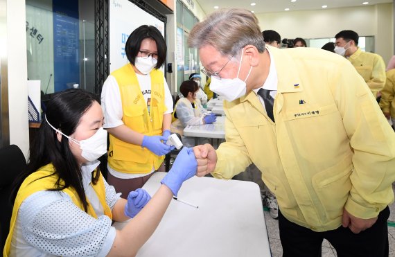 이재명 경기도지사(오른쪽)가 19일 오전 경기도 수원시 장안구 국민체육센터에 설치된 수원시 코로나19 백신 3호 예방접종센터를 방문해 관계자들과 인사를 나누고 있다. 사진=공동취재단