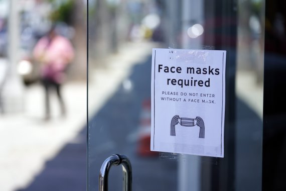 지난 19일(현지시간) 미국 로스앤젤레스의 한 상점 밖에 입장하는 손님들에게 마스크 착용을 권고하는 안내문이 붙어있다. 로스앤젤레스 카운티는 코로나19 확진자 재증가에 실내 마스크 의무화 조치가 내려졌다.AP뉴시스