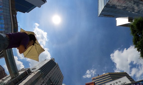 수도권 전지역에 폭염 경보가 내려진 지난 21일 서울 명동 거리에서 한 시민이 양산을 쓰고 이동하고 있다. 기상청은 절기상 가장 더운 날인 대서(大暑)인 22일 일부 내륙지역은 낮 최고기온이 39도까지 오르겠다고 예보했다. 뉴스1