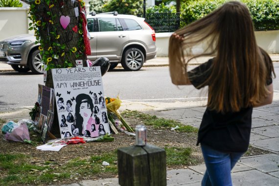 [서울=AP/뉴시스] 영국 R&B 솔 싱어송라이터 에이미 와인하우스가 23일(현지시간) 10주기를 맞았다. 팬들이 런던 캠든에 위치한 와인하우스의 옛집 앞에 남겨진 헌화물을 지켜보고 있다.
