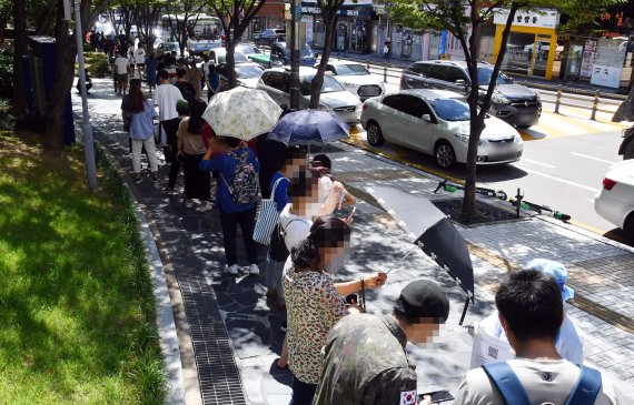 부산지역 코로나19 확산세가 심상치 않은 가운데 26일 오전 부산 남구보건소 선별진료소를 찾은 시민들이 진단검사를 받기 위해 길게 줄을 선 채 차례를 기다리고 있다. 이날 해당 보건소 주변으로 검사 대기 줄이 100m 가량 이어졌다. 사진=뉴시스화상