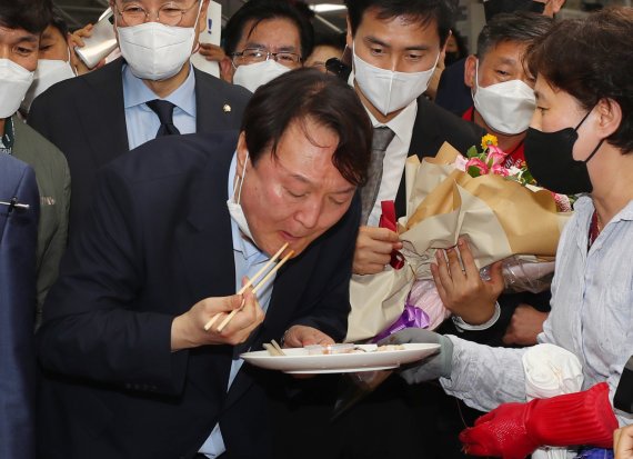 윤석열 전 검찰총장이 27일 오후 부산 중구 자갈치시장을 찾아 상인이 건넨 전복을맛보고 있다. 2021.7.27/뉴스1 © News1 부산사진공동취재단