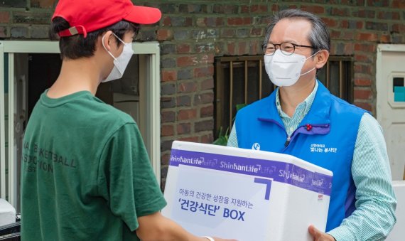 성대규 신한라이프빛나는재단 이사장(오른쪽)이 지난 4일 서울 용산구 아동들에게 건강식단이 담긴 상자를 전달하고 있다. 신한라이프 제공