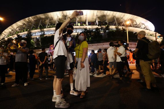 지난 8일 일본 도쿄 신주쿠 국립경기장 앞에서 일본의 시민들이 도쿄올림픽 폐막식 분위기를 즐기고 있다. 로이터 뉴스1