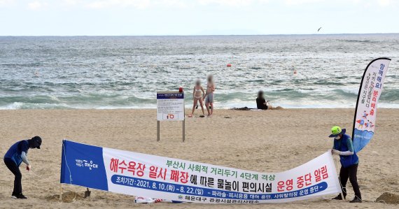 [부산=뉴시스] 하경민 기자 = 부산시는 오는 10일 0시부터 22일 24시까지 사회적 거리두기를 4단계로 격상하고, 부산 7개 해수욕장을 모두 폐장하기로 결정했다. 폐장을 하루 앞둔 9일 오후 해운대해수욕장에서 구청 관계자들이 일시 폐장을 안내하는 현수막을 설치하고 있다. 2021.08.09. yulnetphoto@newsis.com