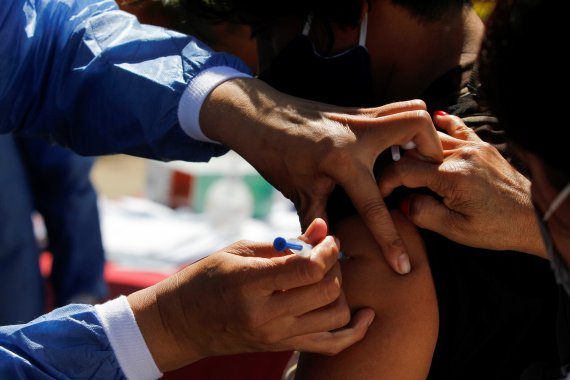 3일(현지시간) 미국과 멕시코 국경인 멕시코 엘 차파랄에서 한 이민자가 미국 의료진으로부터 코로나19 백신을 맞고 있다. 로이터뉴스1