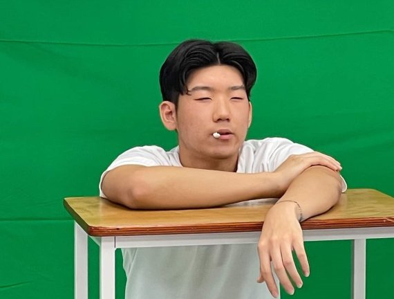 [의정부=뉴시스] 의정부고등학교 학생자치회가 공개한 졸업사진. 한 학생이 '2020도쿄올림픽' 국가대표 야구선수 강백호가 경기 중 덕아웃에 앉아 있는 모습을 패러디 하고 있다. (사진=의정부고 학생자치회 제공)