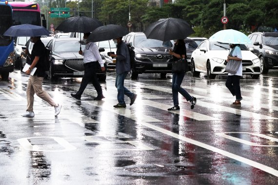 비가 내린 지난 18일 오전 우산을 쓴 시민들이 서울 영등포구 여의도의 한 횡단보도를 걸어가고 있다. 뉴스1