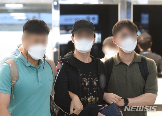 제주 지역 장기미제 '이승용 변호사 살인 사건' 핵심 피의자로 지목된 A(55·왼쪽 두번째)씨가 지난 18일 오후 제주국제공항 1층 도착장에서 경찰에 의해 송환되고 있다. 경찰은 A씨를 1999년 11월5일 발생한 이 변호사 살인사건의 교사범으로 보고 체포영장을 발부받았다. 캄보디아에 불법체류 중이던 A씨는 현지 경찰과 인터폴 적색수배에 따른 강제추방이 결정돼 국내로 송환됐다. 2021.08.20. [뉴시스]