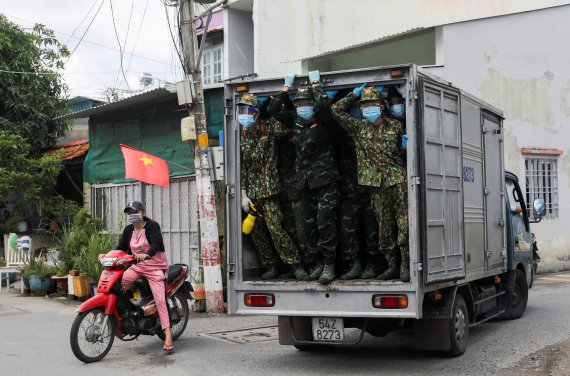 지난 24일 록다운(이동제한)이 실시되고 있는 베트남 호치민시에서 군인들이 시민들에게 배급될 식료품이 실린 화물차를 타고 이동하고 있다.로이터뉴스1