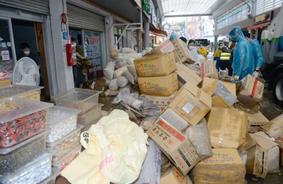 제12호 태풍 오마이스 영향으로 많은 비가 내린 24일 새벽 울산 중구의 태화시장이 침수 피해를 입었다. 자원봉사자들이 비에 젖은 물건을 정리하며 수해 복구에 힘을 보태고 있다.뉴시스