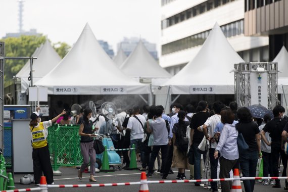 지난 8월 일본 도쿄에 마련된 대규모 백신 접종장 앞에 접종을 위해 줄을 서 있다. AP뉴시스
