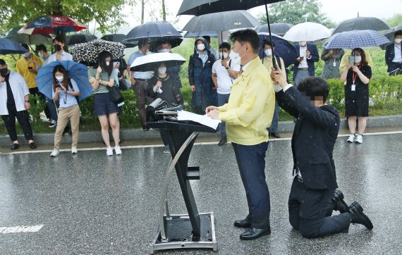 [진천=뉴시스] 강신욱 기자 = 강성국 법무부 차관이 27일 오후 충북혁신도시 국가공무원인재개발원 정문 앞에서 아프가니스탄 특별기여자 초기 정착 지원을 발표하는 브리핑을 하는 동안 한 직원이 뒤쪽에 무릎을 꿇고 우산을 받쳐주고 있다. 이날 강 차관이 발표한 브리핑 자료는 비가 흠뻑 젖었다. 2021.08.27. ksw64@newsis.com /사진=뉴시스