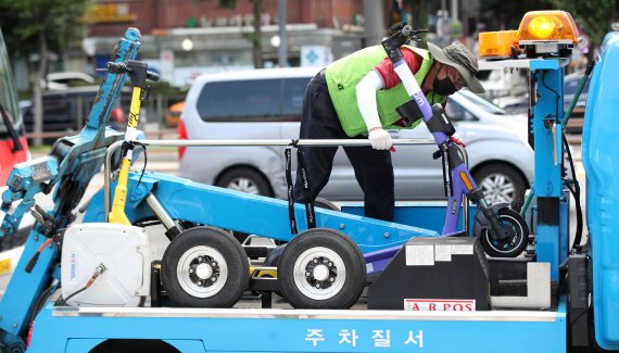 지난 7월15일 오전 서울 송파구 가락시장역 인근에서 송파구청 관계자들이 불법 주·정차 전동킥보드를 단속 및 견인하고 있다. 서울시는 이날부터 성동구·송파구·도봉구·마포구·영등포구·동작구 6개 자치구에서 불법 주·정차된 공유 전동킥보드를 견인을 시작했으며 견인된 공유 전동킥보드 업체에는 견인료 4만원과 보관료(30분당 700원)가 부과된다. 2021.7.15/뉴스1 © News1 조태형 기자