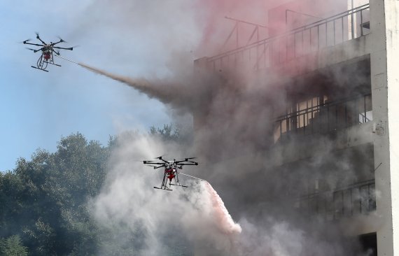 소방 드론 2대가 상공에서 화재가 발생한 건물에 물을 쏘고 있다. 뉴시스