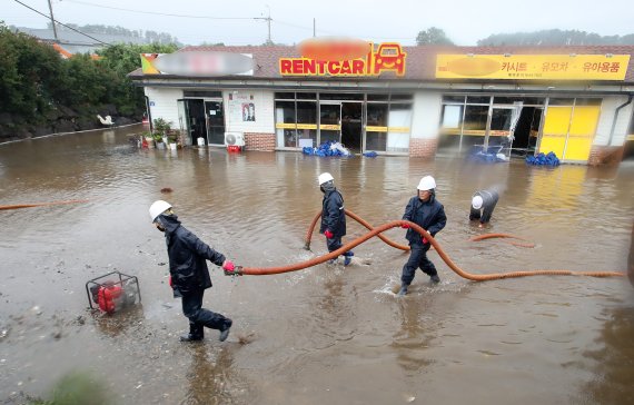 14호 태풍 '찬투'가 몰고 온 많은 비로 지난 17일 제주시의 한 상가 건물이 물에 잠겼다. 관계자들이 배수 복구작업을 하고 있다. 뉴시스