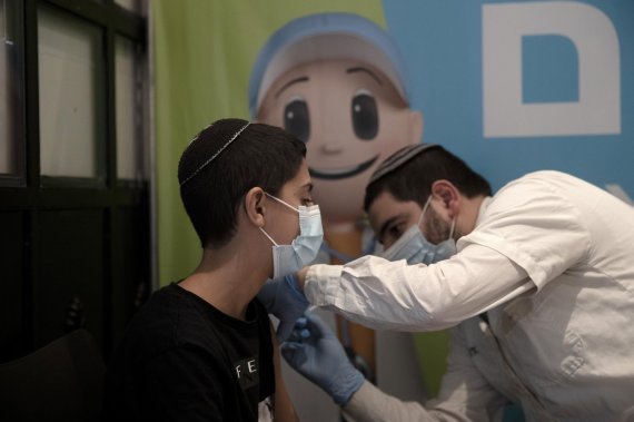 이스라엘 예루살렘의 시네마시티 멀티플렉스 극장에 마련된 코로나19 백신 접종센터에서 22일(현지시간) 14세 소년이 코로나19 백신 부스터샷을 맞고 있다. AP뉴시스