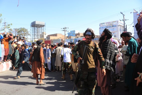 아프가니스탄 서부 도시 헤라트 도심의 한 광장에 25일(현지시간) 주민들이 물려들어 탈레반이 크레인에 매달아 전시한 유괴범 시신을 구경하고 있다. AP뉴시스