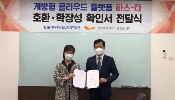 구재학 티맥스클라우드 상무(오른쪽)가 김은주 한국지능정보사회진흥원 김은주 클라우드기술지원단장에게서 개방형 클라우드 플랫폼 파스-타 호환, 확장성 확인서 전달받은 뒤 기념촬영을 하고 있다. 티맥스클라우드 제공