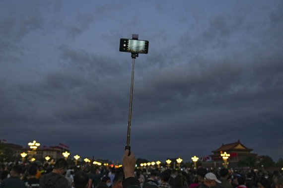 [베이징=AP/뉴시스] 지난 1일 중국 베이징에서 톈안먼광장에서 국기게양식을 기다리면 한 남성이 셀카봉을 들고 있다. 2021.10.02